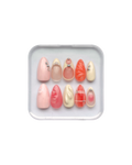 Set of press on nails in orange, pink, pale yellow, and pale pink in a clear plastic case on a white background. Silver and pearl detailing. 